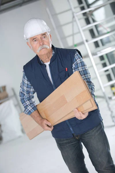 Senior-Schreiner trägt Holzbohlen auf Baustelle — Stockfoto