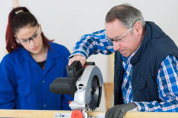 Student and teacher in carpentry class using circular saw — Stock Photo, Image