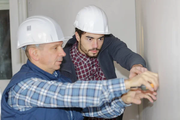 Dos constructores de trabajo aplica pegamento en una pared —  Fotos de Stock