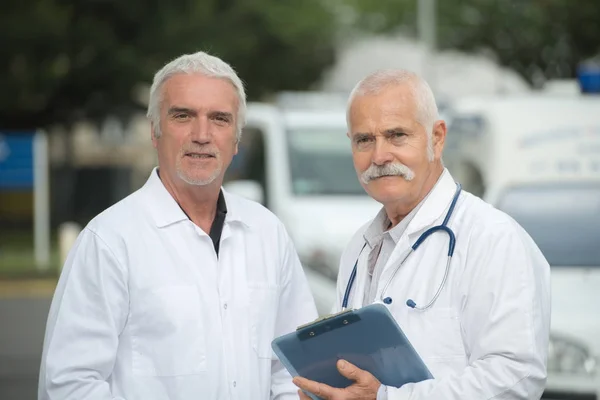 Médicos varones mayores que usan bata de laboratorio blanca fuera del hospital — Foto de Stock