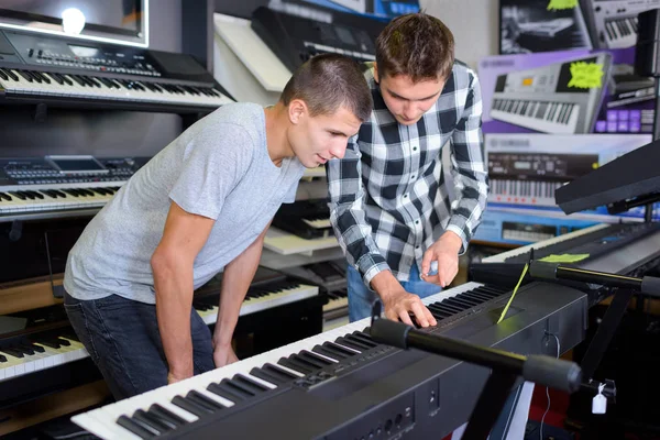 Mladí muži při pohledu na klávesy v hudebním obchodě — Stock fotografie
