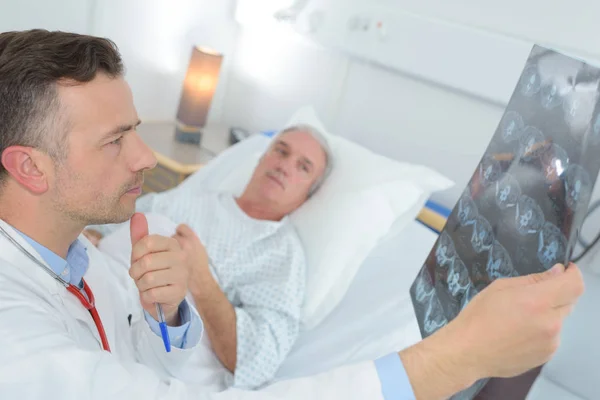 Зрілий лікар оглядає пацієнтів рентген в лікарні — стокове фото