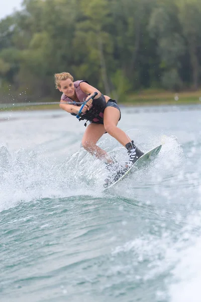 Wakeboarder feminino fazendo truques em um lago — Fotografia de Stock