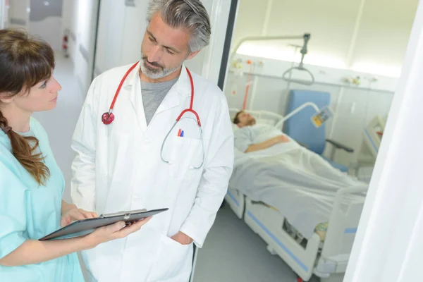 Arzt und Krankenschwester diskutieren über Notizen auf Klemmbrett — Stockfoto