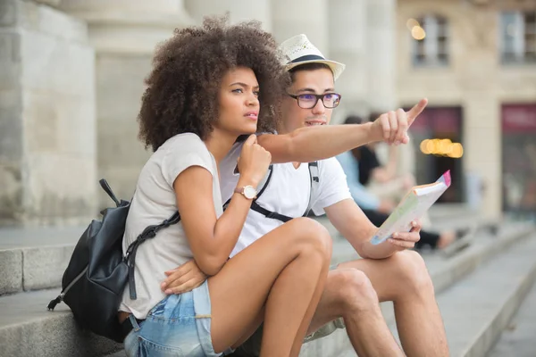 Par av turister tittar på stadsguide — Stockfoto