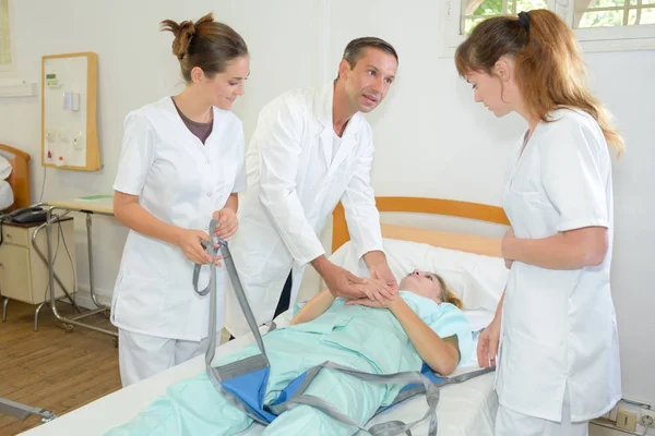 Médico mostrando às enfermeiras estudantes como levantar pacientes — Fotografia de Stock