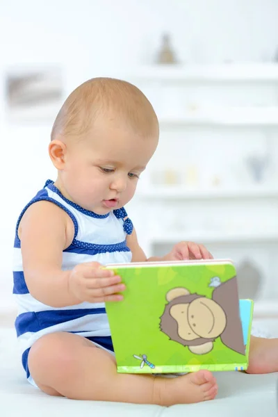 Baby nieuwsgierig met een boek — Stockfoto