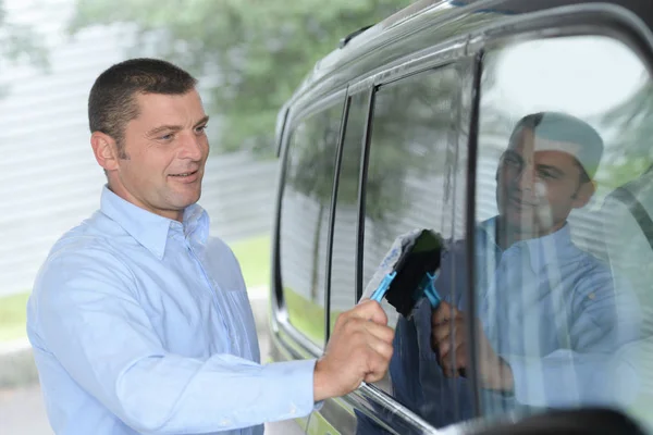 Man hand rengöring bil fönster med blå mikrofiber trasa — Stockfoto