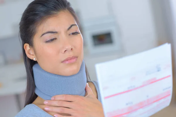 Jeune femme portant cou orthèse lecture lettre d'assurance — Photo