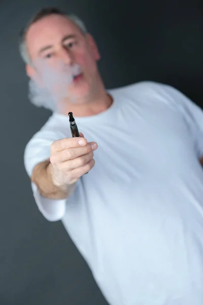 Ο άνθρωπος κατέχει ένα ηλεκτρονικό τσιγάρο που εκπνέετε ένα σύννεφο των ατμού — Φωτογραφία Αρχείου