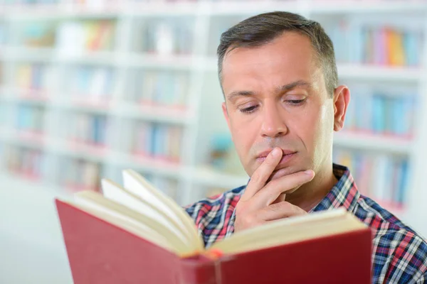 Homme lisant le livre dans la bibliothèque — Photo