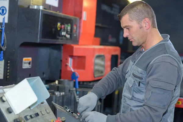 Pracownik w rękawice ochronne w fabryce przy użyciu maszyny — Zdjęcie stockowe