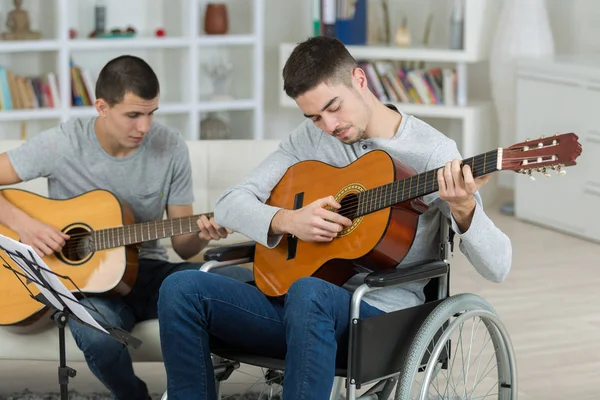 Νέοι άνδρες που παίζει κιθάρα, ένα σε μια αναπηρική καρέκλα — Φωτογραφία Αρχείου
