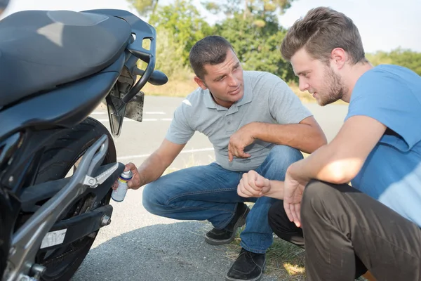 Uomo e amico riparazione danneggiato motore moto — Foto Stock