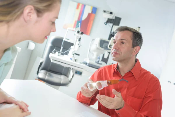 Mann som diskuterer øyeklær med optiker – stockfoto