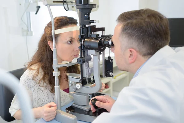 Optometrista examinando paciente femenina en foropter — Foto de Stock