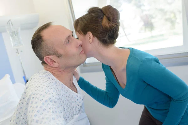 Wife kissing sick husband on hospital bed — Stock Photo, Image