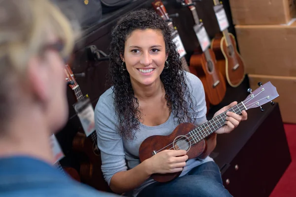 Heureux client féminin essayant de jouer de la guitare en magasin — Photo