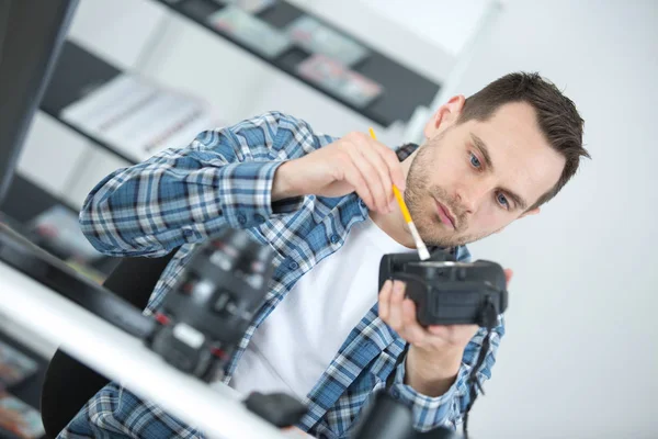 Ο άνθρωπος τον καθαρισμό του φακού από την ψηφιακή φωτογραφική μηχανή με το ειδικό πινέλο — Φωτογραφία Αρχείου