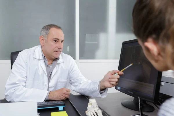 Doutor mostrando raio-x para seu paciente em consultório médico — Fotografia de Stock