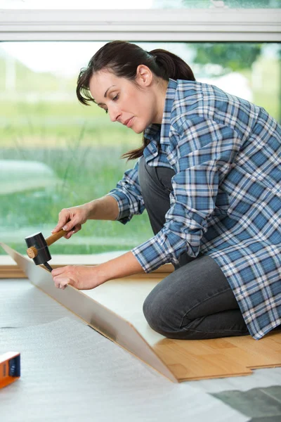 Mujer instalación de pisos de madera laminada nueva — Foto de Stock