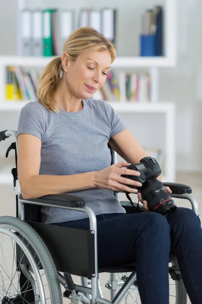 Fotograf kobieta na wózku inwalidzkim, trzymając aparat profesjonalny — Zdjęcie stockowe