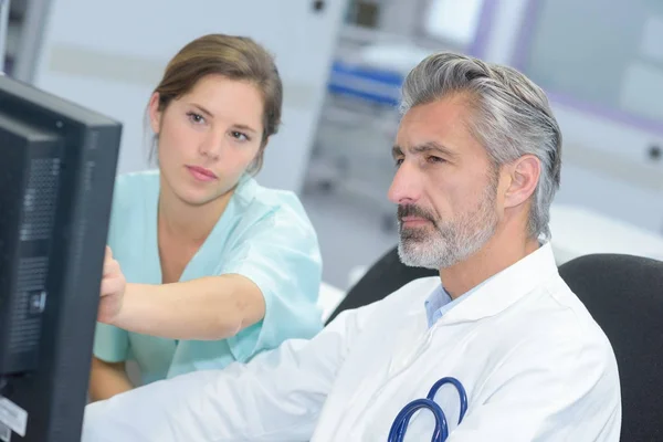 Médecin et infirmière vérifiant les dossiers informatiques — Photo