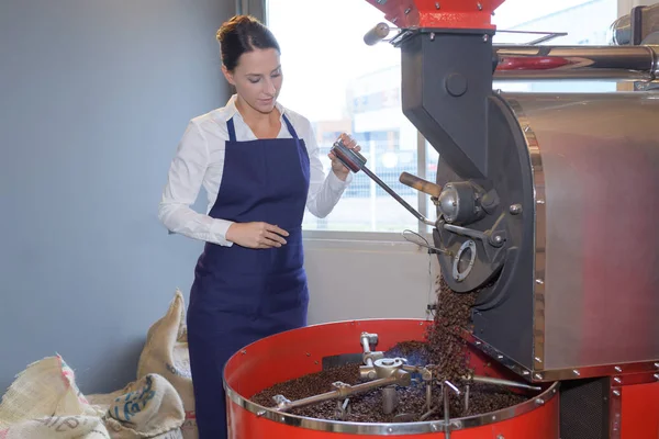 Travailleuse torréfiant des grains de café dans une usine — Photo