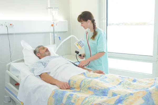 Patient couché sur le lit à côté de l'infirmière dans la salle d'hôpital — Photo