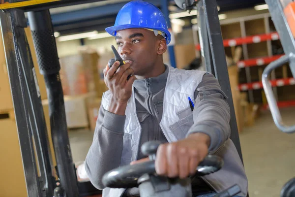 Autista di carrelli elevatori nel magazzino logistico industriale guardando la telecamera — Foto Stock