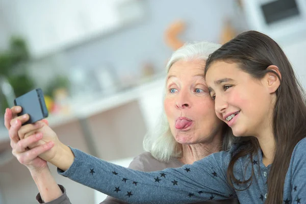 Äldre kvinna att göra selfie med dotterdottern unga hemma — Stockfoto