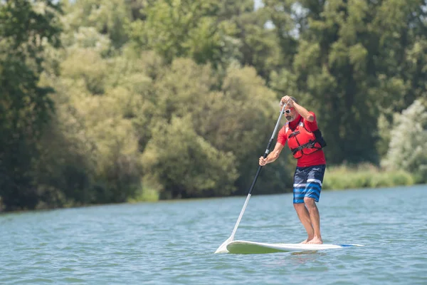Mature attractive rider contemplating nature sitting on paddle board — Stock Photo, Image
