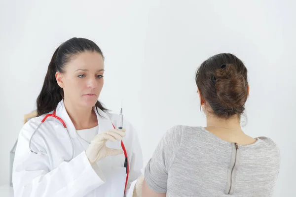 Γυναίκα γιατρό με σύριγγα μπροστά από ασθενή — Φωτογραφία Αρχείου