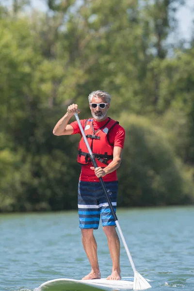 Człowiek cieszyć jazdą na jeziorze z paddleboard — Zdjęcie stockowe