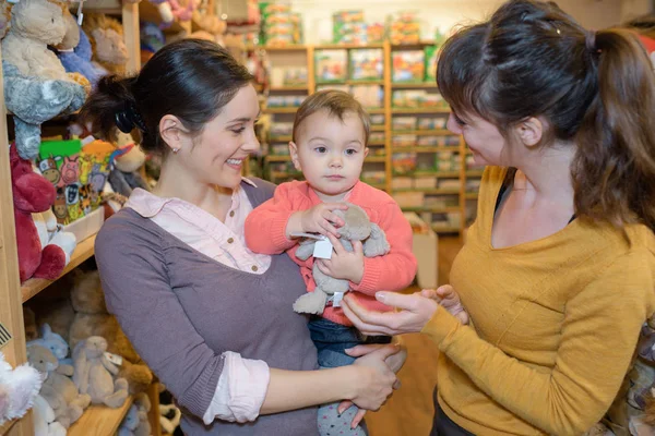 Μητέρα και κόρη με ελκυστικό πωλητής σε κατάστημα παιχνιδιών — Φωτογραφία Αρχείου