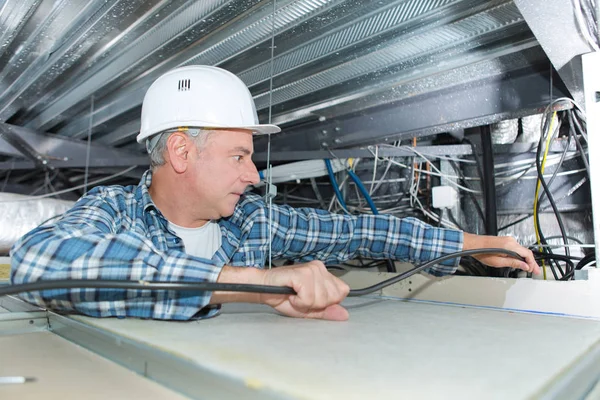 Férfi javítása elektromos vezetékek a mennyezeten — Stock Fotó