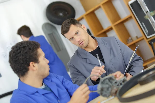 Mécanicien et apprenti travaillant sur la pièce de voiture — Photo