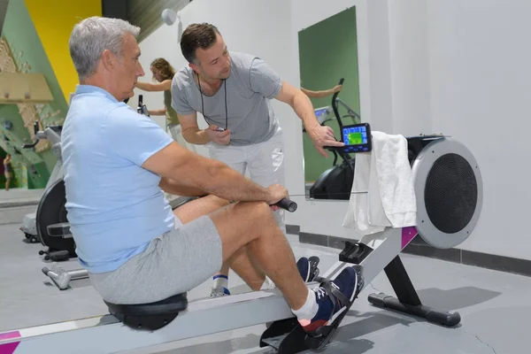 Senior man in sportschool gebruik van een roeiapparaat — Stockfoto