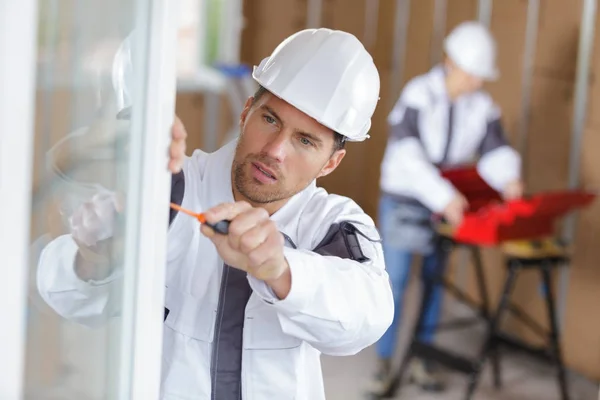 Trabajador de la construcción instalando ventana en casa — Foto de Stock