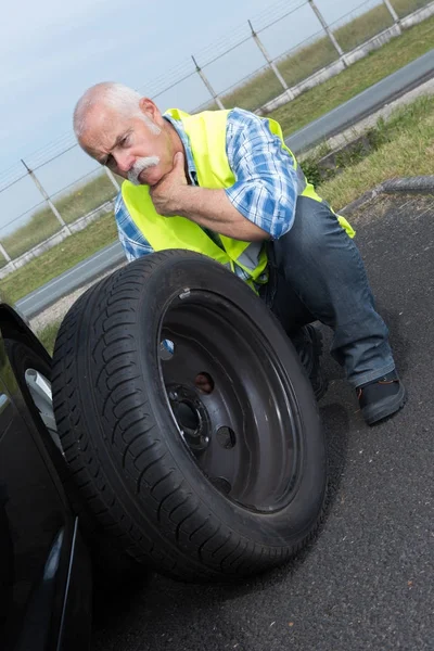 Mutloser Rentner kann Autoreifen nicht wechseln — Stockfoto