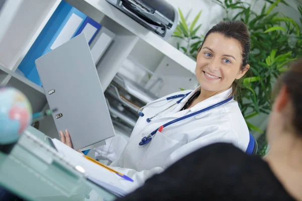 Sorridente médico feminino com uma pasta em seu escritório — Fotografia de Stock