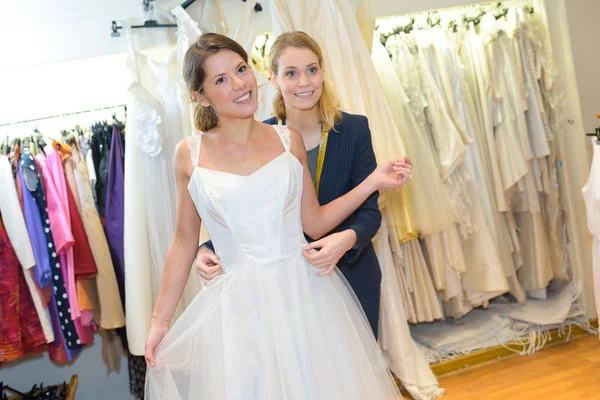 Fêmea tentando no vestido de noiva com costureira — Fotografia de Stock