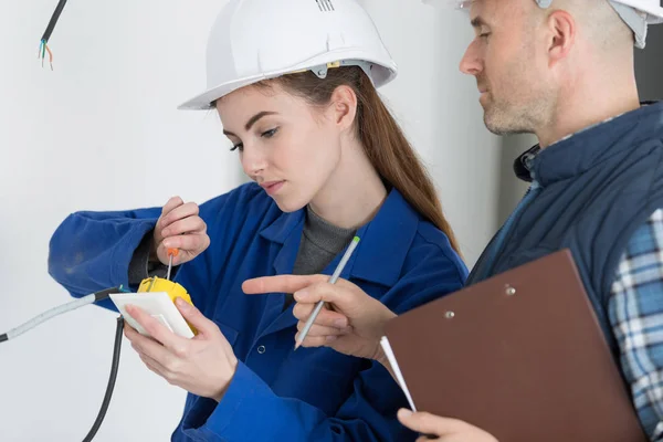 Elektricien en zijn vrouwelijke leerling afregelen socket — Stockfoto