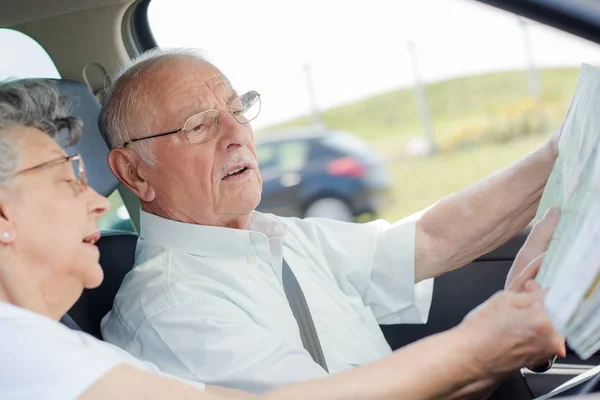 지도 확인 하는 동안 자동차를 운전 하는 노인 — 스톡 사진