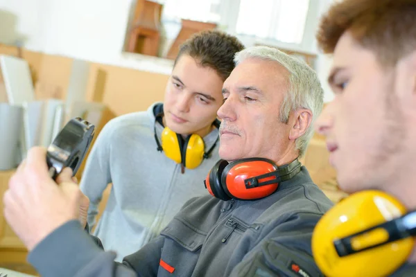 Hombre con aprendices sosteniendo rodamientos —  Fotos de Stock