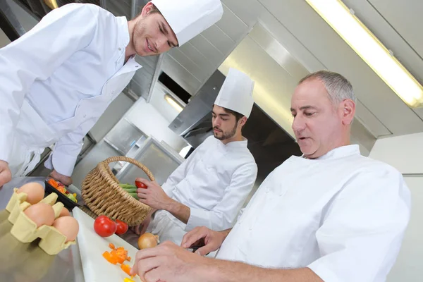 2 aprendizes cozinheiros aprendendo com mestre chef — Fotografia de Stock