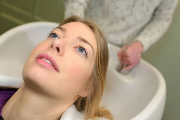 Estilista lavando y peinando cabello de mujer en la piscina de peluquería — Foto de Stock