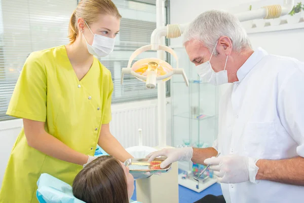 Criança em cadeira dentária com dentista após a reparação dos dentes — Fotografia de Stock