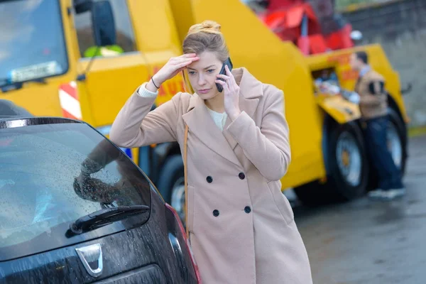 Worried woman on telephone, breakdown lorry in background — Stock Photo, Image