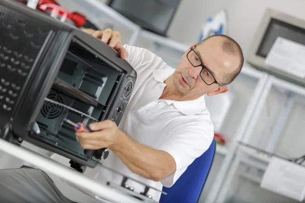 Reparador trabajando en un microondas en la cocina —  Fotos de Stock